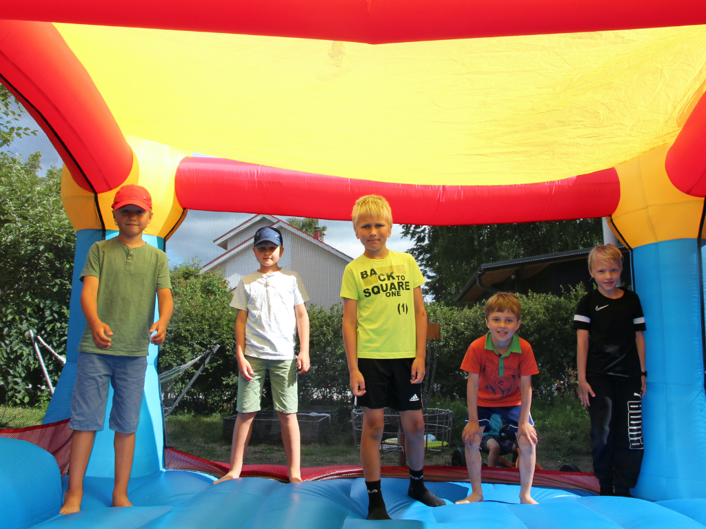 Pojat hyppivät pomppulinnassa kesäleirillä.